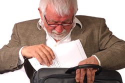 Tips on how to write a grant proposal. A male professor is placing a grant proposal into his briefcase.