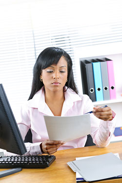 Scribendi.com's editors explain everything you need to know about copy editing. A young woman with brown hair is sitting at a desk copy editing some papers.