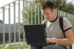 Our editors explain what expository writing is. A young college student sitting outsite with a A young college student sits outside with a backpack and laptop, writing his expository essay.