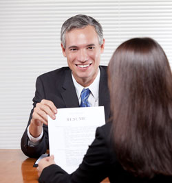 Our editors provide a sample resume to help you with the resume writing process. A man is handing a sample resume to a colleage for her to review.