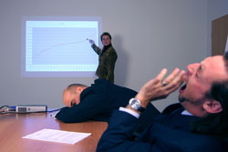 Two bored men listening to a PowerPoint presentation in an office.