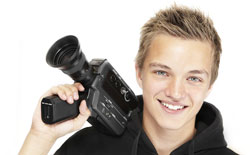 A young man holds a camera and looks straight ahead; he is participating in Script Frenzy.