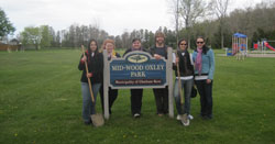 Scribendi.com staff members stand with a sign in a Chatham park that reads: "Mid-Wood Oxley Park."