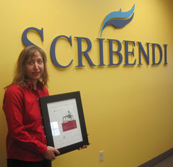 Scribendi.com President Chandra Clarke holds the VeriSign Certificate. She is standing in front of a Scribendi sign.