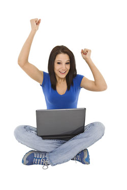 A young woman is sitting on the floor with her labtop. Her arms are up in the air and she is smiling because of Scribendi.com's new website launch.