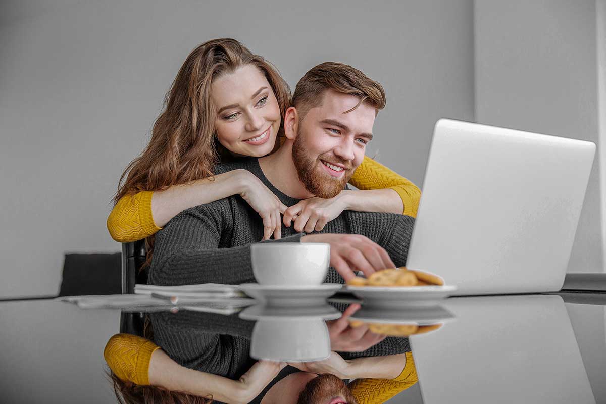 A happy couple looking at a laptop.
